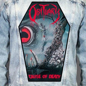 May include: A light blue denim jacket featuring a large, coffin-shaped back patch. The patch displays a dark, surreal illustration with a giant red eye, a figure trapped in webbing, a gnarled tree with skulls, and the text OBITUARY and CAUSE OF DEATH.