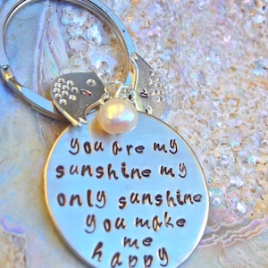 May include: Silver keychain with a pearl charm and a metal tag that reads "You are my sunshine my only sunshine you make me happy".