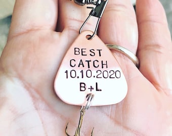 Op de afbeelding: Een koperkleurige vislokaas met een driehoekig lichaam en een haak. Het lokaas is gegraveerd met de tekst "BEST CATCH 10.10.2020 B+L".