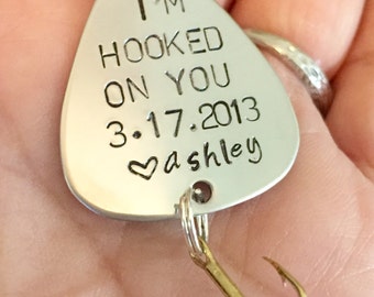May include: Silver fishing lure keychain with the text "I'm hooked on you 3.17.2013 ashley" and a heart symbol.