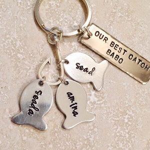 May include: Silver keychain with a fish-shaped charm that says "Our Best Catch" and three smaller fish charms that say "Sead", "Seadan", and "Am-ina".