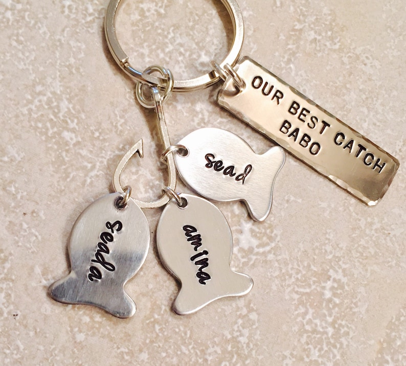 May include: Silver keychain with a fish-shaped charm that says "Our Best Catch" and three smaller fish charms that say "Sead", "Seadan", and "Am-ina".