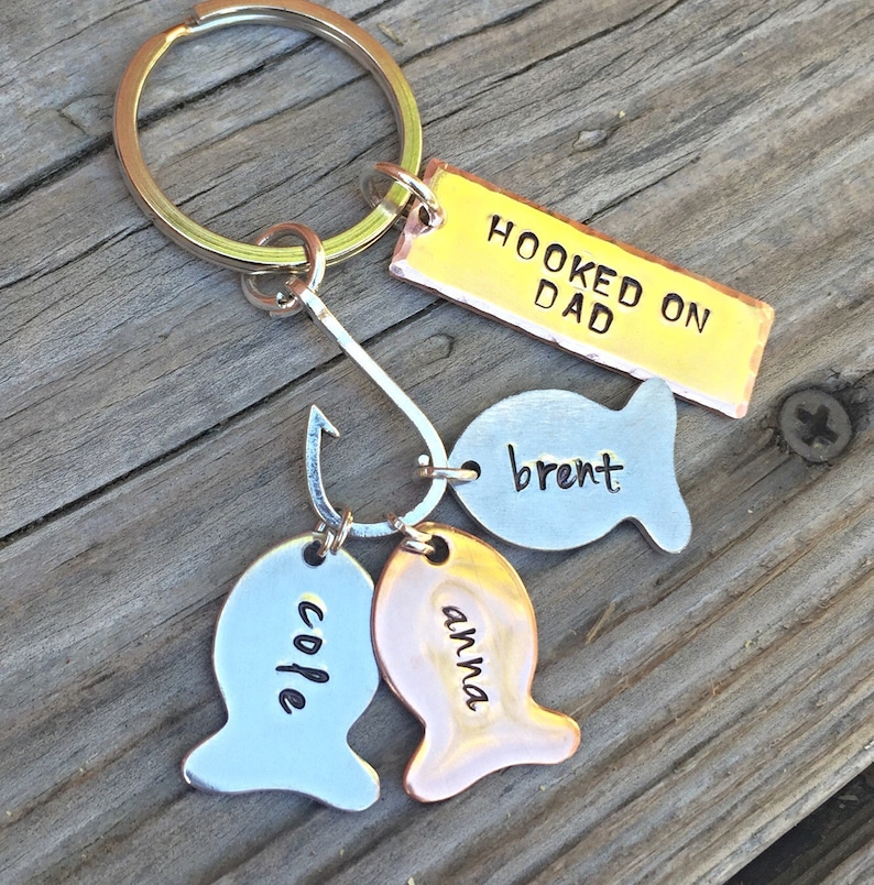 May include: A gold keychain with the words "Hooked on Dad" and three fish charms with the names "Brent", "Anna", and "Cole" engraved on them.