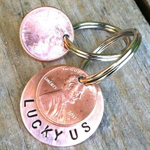 May include: A copper penny keychain with the words "Lucky Us" engraved on the back. The keychain is made from two pennies, one with the inscription "In God We Trust" and the other with the inscription "Liberty 2011".