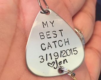 Op de afbeelding: Een zilveren vislood met een hart en de tekst "My Best Catch 3/19/2015 Jen" erop gegraveerd.