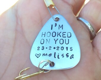 Op de afbeelding: Zilveren vislood met een gouden haak en een zilveren ketting. Het lood heeft de tekst "I'm Hooked On You 23.2.2015 ♥ melissa" gegraveerd.