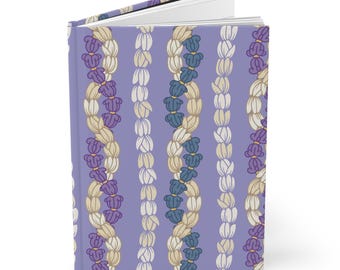 Può includere: Un diario con copertina rigida con una copertina lavanda con un motivo ripetuto di ghirlande floreali stilizzate in viola, crema e blu. Il diario è aperto, rivelando pagine bianche.