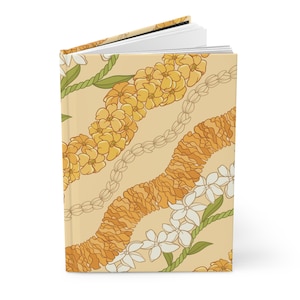 May include: A yellow and white floral patterned journal with a soft, cream-colored cover. The pattern features a repeating design of flower leis.