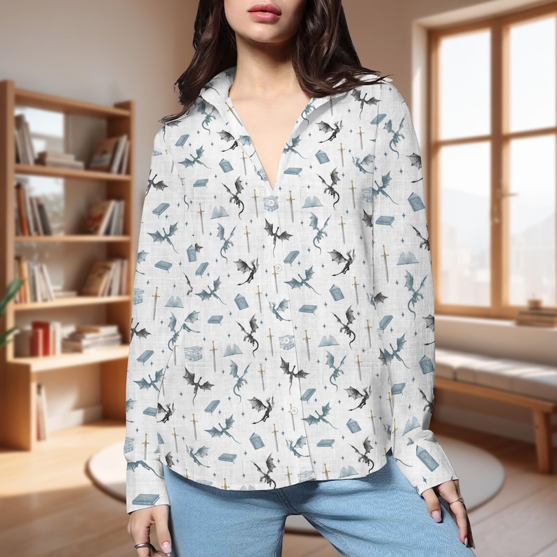 May include: White button-down shirt with a repeating pattern of dragons, swords, books, and mountains in shades of blue and gray. The long-sleeved shirt is made of a lightweight fabric.