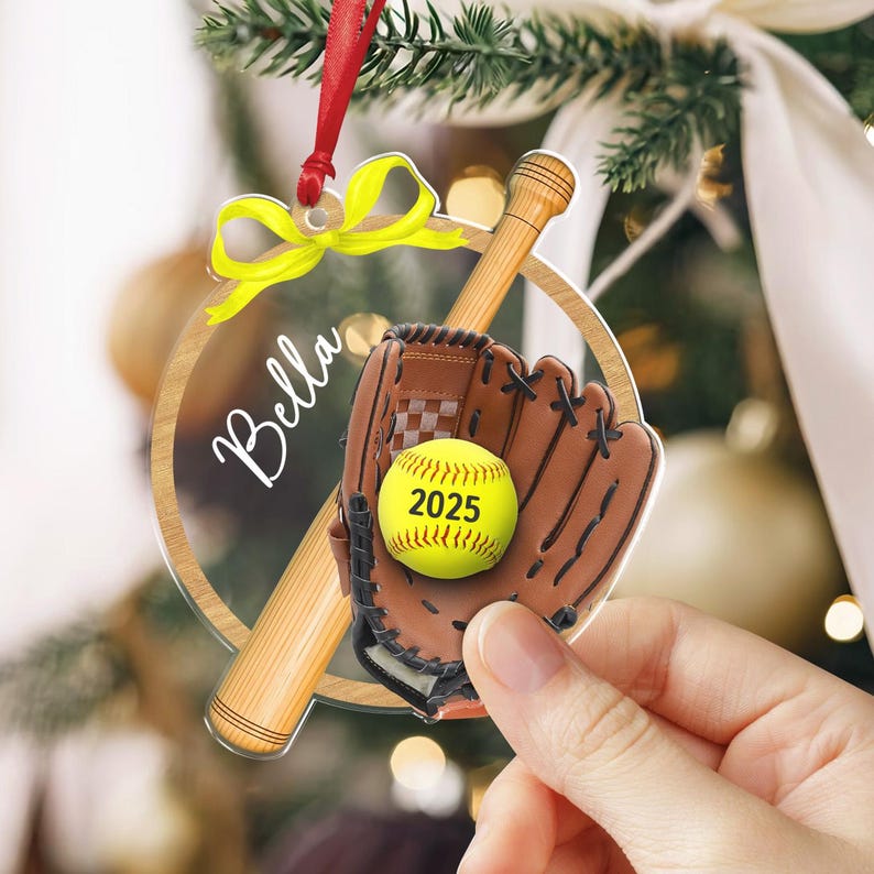 Pode incluir: Um enfeite de softball de acr&iacute;lico transparente com um bast&atilde;o de beisebol de madeira, uma luva marrom e uma bola de softball amarela. A bola mostra o ano de 2025. O enfeite &eacute; decorado com um la&ccedil;o amarelo e uma fita vermelha.