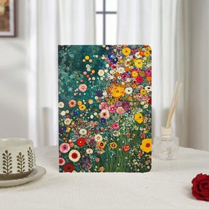 May include: A notebook with a colourful floral design, featuring a variety of flowers in shades of yellow, pink, red, and white. The cover has a teal background. The notebook is displayed on a white surface.