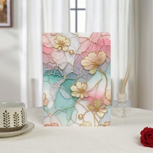 May include: A decorative rectangular panel with a floral design. The panel features gold-coloured flowers and pearl accents against a backdrop of pink, blue, and white abstract shapes. The panel is on a white surface.