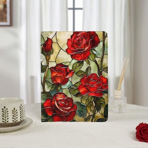 May include: A rectangular tablet case featuring a stained glass pattern of vibrant red roses with green leaves against a pale yellow and cream background. The design uses dark lead-like lines to separate the floral and foliage segments.