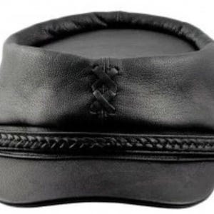 May include: Black leather hat with a rounded crown and a braided band around the base. The hat features a decorative cross-stitch detail on the front. The hat is a dark, solid color.