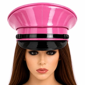 Può includere: Un berretto in stile militare in vernice rosa brillante con una finitura lucida. Il cappello presenta una visiera in vernice nera e un cinturino decorativo nero abbinato sulla parte anteriore, fissato con piccoli bottoni neri.