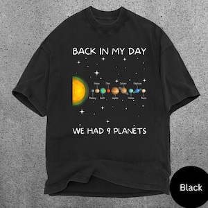 May include: Black t-shirt featuring a solar system graphic with the text "BACK IN MY DAY WE HAD 9 PLANETS". The design includes the sun, planets, and stars.