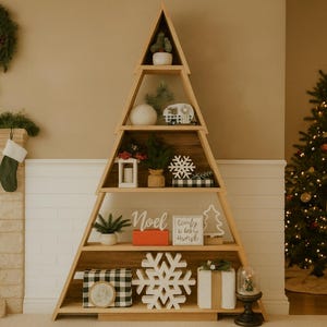 Puede incluir: Estantería de madera con forma de árbol de Navidad llena de adornos navideños. Incluye una pequeña planta en maceta, un copo de nieve blanco, una caja a cuadros en blanco y negro y un letrero que dice "Noel".