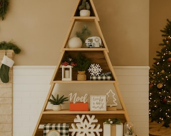 May include: Wooden Christmas tree-shaped shelf filled with holiday decorations. Includes a small potted plant, a white snowflake, a black and white checkered box, and a sign that says "Noel".