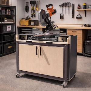 May include: A miter saw mounted on a rolling cabinet. The saw is orange and silver, with a large circular blade. The cabinet has two doors with black handles and is made of light-colored wood. The cabinet is on wheels.
