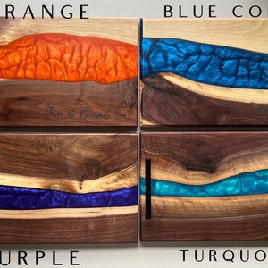 May include: Four wooden serving boards with different colored epoxy resin inlays. The boards are labeled "Orange", "Blue Coral", "Purple", and "Turquoise".