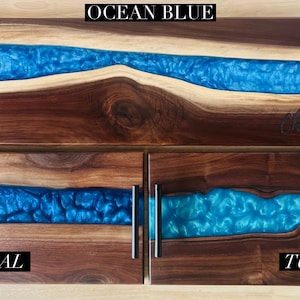 May include: Three wooden serving trays with blue resin inlays. The top tray is labeled "OCEAN BLUE", the middle tray is labeled "BLUE CORAL", and the bottom tray is labeled "TURQUOISE".