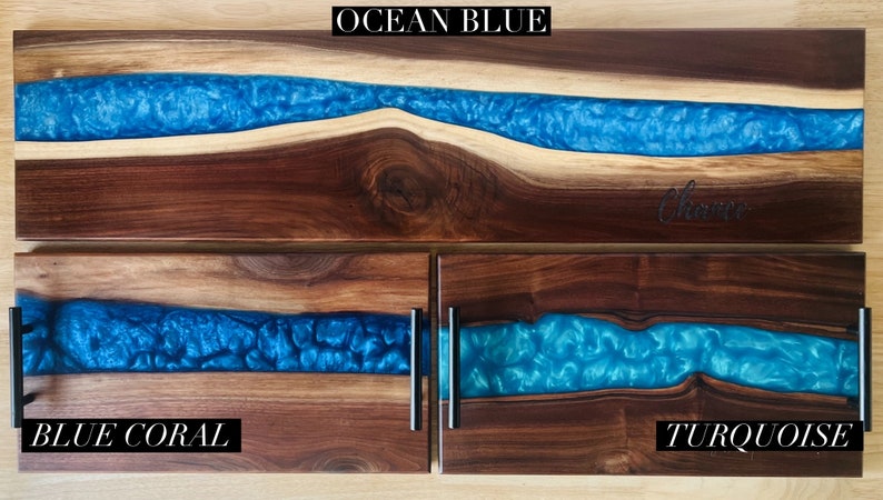 May include: Three wooden serving trays with blue resin inlays. The top tray is labeled "OCEAN BLUE", the middle tray is labeled "BLUE CORAL", and the bottom tray is labeled "TURQUOISE".