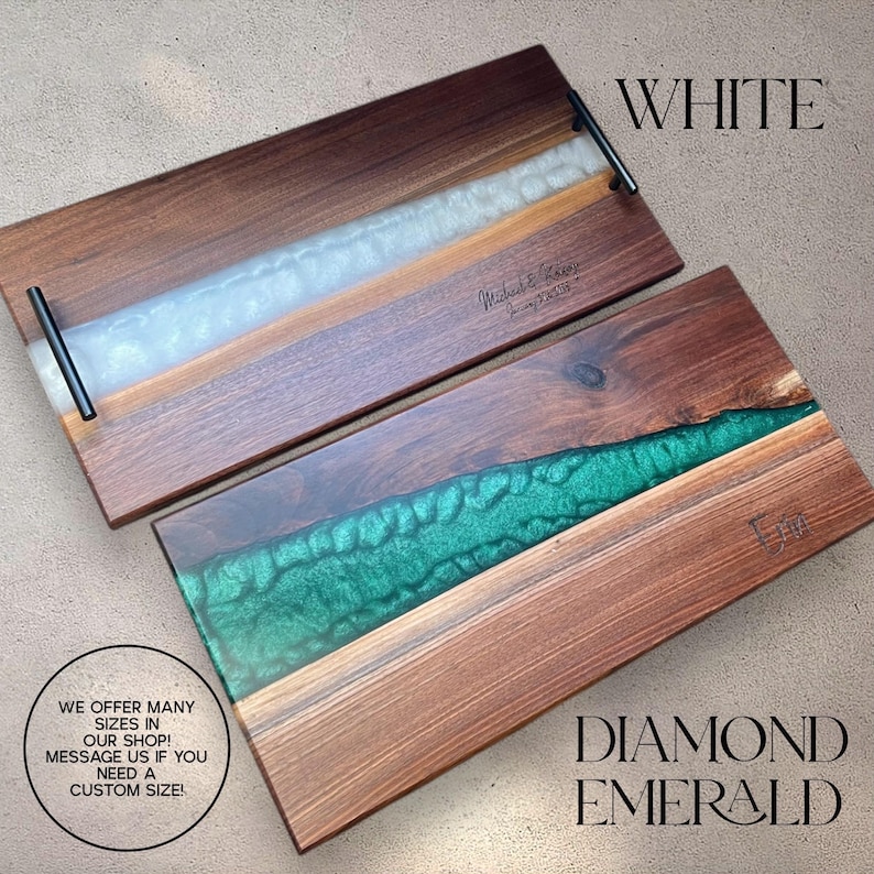 May include: Two wooden serving trays with epoxy resin inlays. The top tray has a white epoxy inlay and the bottom tray has a green epoxy inlay. Both trays have black metal handles. The text "WHITE" is written above the top tray and the text "DIAMOND EMERALD" is written below the bottom tray. The text "WE OFFER MANY SIZES IN OUR SHOP! MESSAGE US IF YOU NEED A CUSTOM SIZE!" is written in the bottom left corner of the image.