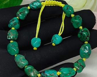 May include: A turquoise bead bracelet with a yellow adjustable cord. The bracelet features irregularly shaped, vibrant green-blue beads with dark matrix patterns. The beads are strung together with yellow cord, creating a striking contrast. The bracelet is displayed on a black surface.