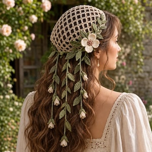 Può includere: Una retina per capelli all'uncinetto color beige con motivo a griglia, decorata con un grande fiore all'uncinetto color crema e diversi lunghi viticci verdi all'uncinetto con piccoli boccioli color crema che scendono lungo la schiena.