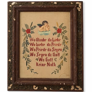 May include: A framed artwork featuring a cherub on a cloud, surrounded by floral elements. The artwork has text in red, with a dark brown frame. The background is a light tan color.