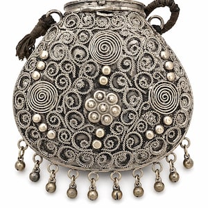 May include: Ornate silver-toned metal purse with intricate scrollwork and spiral designs. The purse features small dangling bells along the bottom edge and a braided handle. A decorative and functional accessory.