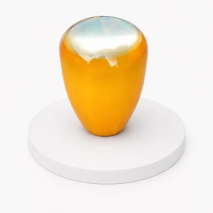 May include: A vibrant, orange-yellow decorative vase with a pearlescent, light blue and white top. The vase is set on a white, circular pedestal against a white background. The smooth, glossy surface reflects light.