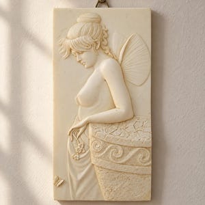 Puede incluir: Una placa de pared rectangular de color blanco roto con un bajorrelieve de una figura con alas, el pelo recogido y una prenda drapeada. La figura se apoya en una estructura texturizada con patrones de ondas, sosteniendo pequeñas flores.
