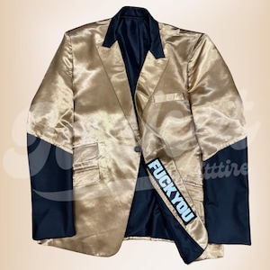 Op de afbeelding: Gouden satijnen blazer met zwarte accenten op de mouwen en kraag. De blazer heeft een sluiting met één knoop en een patch met de tekst "FUCK YOU".