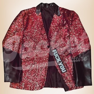 Op de afbeelding: Een rode blazer met pailletten met zwarte leren mouwen en kraag. De blazer heeft een sluiting met één knoop en een patch met de tekst "FUCK YOU". De jas is een gedurfd fashion statement.