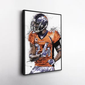 May include: Framed artwork featuring a football player in an orange and blue uniform with the number 24. The player is wearing a helmet with a Broncos logo. The artwork has a watercolor effect with paint splatters.