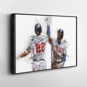 May include: A framed print featuring two baseball players in action, celebrating a play. One player wears a jersey with "OLSON" and the number "28". The artwork has a watercolor effect with splashes of color against a white background.