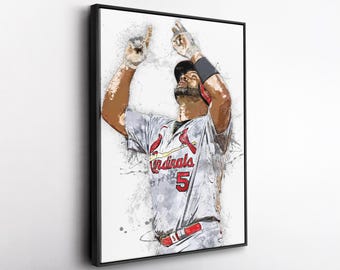 以下が含まれることがあります： 「Cardinals」の文字と数字の「5」が入ったグレーのユニフォームを着た野球選手の額装アート。 選手は両腕を上げて祝っています。 アートワークは、赤とグレーのアクセントを持つ水彩効果があります。