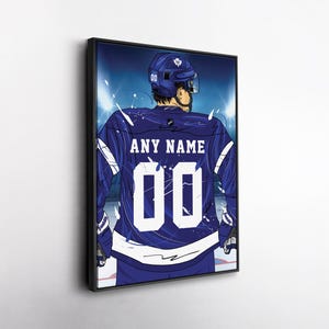 May include: Framed artwork of a hockey player in a blue jersey with the text "ANY NAME" and the number "00". The player is viewed from the back, with a helmet and gloves. The background features stadium lights and a blue hue.