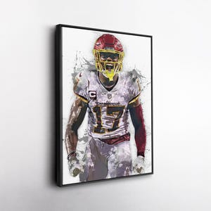 May include: Framed artwork of a football player in a Washington Commanders uniform. The player is wearing a red helmet and the number 17. The artwork has a watercolour effect with splashes of colour.