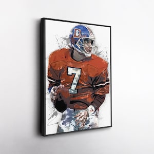 May include: Framed art print of a football player in an orange jersey with the number 7. The player is wearing a blue helmet with a white facemask and the letter "D". The artwork has a watercolor effect with paint splatters.