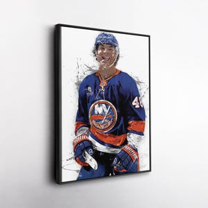 May include: Framed artwork of a hockey player in a blue and orange jersey with the number 41. The jersey features the New York Islanders logo. The player is wearing a helmet and gloves, with a white and grey splatter effect in the background.