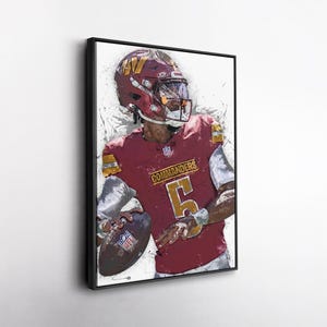 May include: Framed artwork of a football player in a burgundy uniform with the number 5. The player is wearing a burgundy helmet with gold accents. The word "Commanders" is visible on the jersey. The artwork has a white background with paint splatter effects.