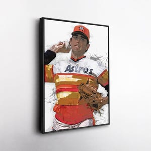 May include: Framed artwork of a baseball pitcher in an Astros uniform. The artwork features the word "Astros" across the chest, a red cap, and a brown baseball glove. The image has a watercolor effect with splashes of color.