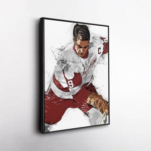 May include: Framed artwork depicting a hockey player in a watercolour style. The player is wearing a white jersey with red details and the number 9. The artwork is in a black frame against a white background.
