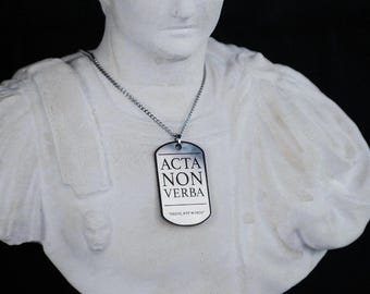 Collar con placa de identificación estoica: "acta non verba" (hechos, no palabras).