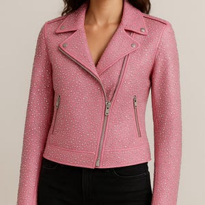 May include: Pink studded biker jacket with a silver zipper and pockets. The jacket has a classic asymmetrical design with a notched collar and snap details. The jacket is worn with black jeans.