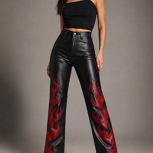 May include: Black high-waisted pants featuring a straight-leg cut and a smooth finish. The lower portion of each pant leg is decorated with a prominent red flame pattern that extends from the hem upward, contrasting against the black base.