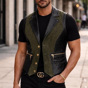 May include: A sleeveless vest featuring a combination of olive green suede panels and black crocodile-embossed leather sections. The vest includes a notched lapel, four gold-toned buttons for closure, and two horizontal zippered pockets with gold hardware.