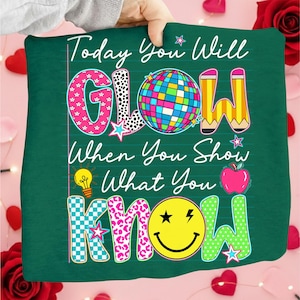 May include: A green pillow with the text "Today You Will GLOW When You Show What You KNOW." The word "GLOW" features a disco ball, pencil, and star. The word "KNOW" has a smiley face and apple.